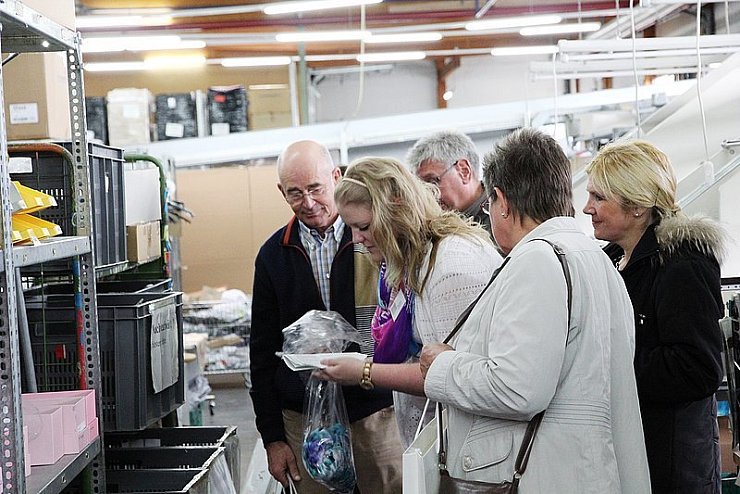 Azubi Nina Büker (mitte) erklärt Heinz Brinkmeier (links) und anderen Teilnehmern, warum Modestücke von Kunden zurückgeschickt werden - beobachtet von "Alba Moda"-Sprecherin Marita Klawun (Zweite von rechts). - © Foto: Beckschäfer
