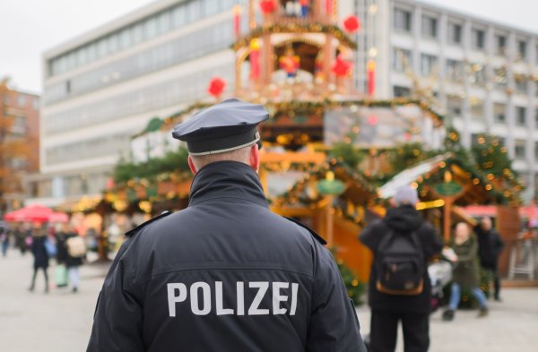 Ein Polizist steht auf einem Weihnachtsmarkt. - © Julian Stratenschulte/dpa/Symbolbild