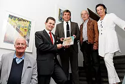 B&uuml;rgermeister Christian Liebrecht (Mitte) &uuml;berreicht Sparkassendirektor Arnd Paas (Zweiter von rechts) das Werkverzeichnis von Sybille Dotti. Im Hintergrund sind deren Bilder "Karussell" und "Stilleben mit Goldhaube" zu sehen. Zweiter von rechts der Vorsitzende der Kunststiftung Matthias Hosenfeldt, links sein Stellvertreter Wilhelm B&uuml;ker, rechts Schriftf&uuml;hrerin Karin Schmidt. - &copy; Foto: Becker