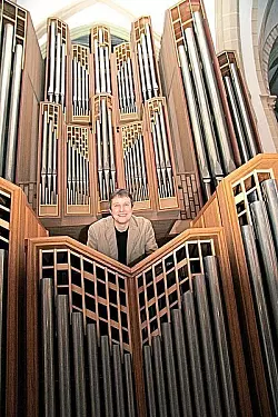 Kantor Friedemann Engelbert beugt sich über eine der beiden Steinmann-Orgeln (Baujahr 1993) in der Kirche St. Nicolai. Im Hintergrund ist das große Instrument (aus 1968, überarbeitet 2009) zu sehen. - © Foto: Reineke