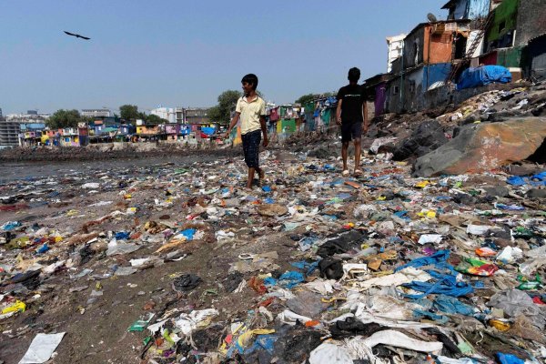 Menschen spazieren am Strand des Badhwar Park im indischen Mumbai an Plastikmüll vorbei. (Archivbild) - © Rajanish Kakade/AP/dpa