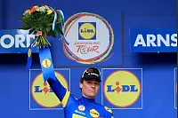 22.08.2025, Nordrhein-Westfalen, Arnsberg: Radsport, Deutschland Tour, Herford - Arnsberg (190,30 km), 2. Etappe, Søren Wærenskjold aus Norwegen vom Team Uno-X Mobility jubelt im blauen Trikot des Gesamtführenden nach der Etappe auf dem Podium. Foto: Jan Woitas/dpa +++ dpa-Bildfunk +++ - © Jan Woitas/dpa