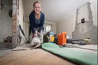 Sch&ouml;ne &Uuml;berraschung: Unter dem grasgr&uuml;nen Teppichboden im Wohnzimmer hat Bauherrin Helga Gerster bei der Sanierung wundersch&ouml;nes Fischgr&auml;t-Eichenparkett gefunden. Immer interessiert mit dabei: ihre H&uuml;ndin Lilli. - &copy; Mike-Dennis Mueller