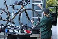 Leon Schmitz steht am hinteren Teil des Vans, an dem auch ein Fahrradträger installiert ist. - © Lena Kley