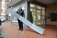 Dieses zwei Meter lange Blech flog vom Dach eines benachbarten Hauses gegen die Schaufensterscheibe des Optikers Karbach in Lage geflogen. Inhaber Thomas Redeker ist froh, dass niemand verletzt wurde. - © Wolfgang Becker