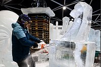 Mit einer Kettensäge bringt eine Künstlerin bei minus 8 Grad einen Eisblock in Form - daraus soll eine Baby-Giraffe werden. - © Christoph Reichwein/dpa