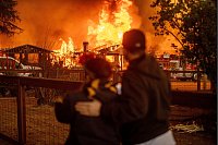 Menschen beobachten, wie das Eaton-Feuer in Los Angeles ein Gebäude verschlingt. - © Ethan Swope/AP/dpa
