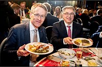 Daniel Günther (l), der Ministerpräsident von Schleswig-Holstein, ist der neue Oldenburger Grünkohlkönig. Hier beim Essen mit dem Oldenburger Oberbürgermeister Jürgen Krogmann (SPD). Auf den Tellern haben sie eine Portion Grünkohl und den klassischen Beilagen Kartoffeln, Pinkel, Kochwurst und Kassler. - © Hauke-Christian Dittrich/dpa