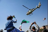Konflikt in Syrien - Damaskus: Ein Hubschrauber der syrischen Armee wirft Blumen und Konfetti auf eine Gruppe von Demonstranten, die den 14. Jahrestag des Beginns des Aufstands gegen das Regime von Assad im März 2011 feiern, auf dem Umayyad-Platz. - © Ghaith Alsayed/AP/dpa