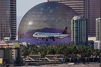 Im Anflug: Ein Flugzeug landet auf dem Harry Reid International Airport von Las Vegas. Im Hintergrund ist die „Sphere at The Venetian Resort“ zu sehen, eine riesige Konzerthalle und Event-Arena in Kuppelform. - © John Locher/AP/dpa