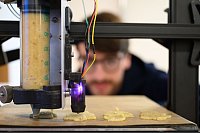 Plätzchen aus dem 3D-Drucker: Ein wissenschaftlicher Mitarbeiter der Professur Additive Fertigung an der TU Bergakademie Freiberg betrachtet die Herstellung von Plätzchen mit einem mobilen 3D-Drucker. - © Robert Michael/dpa