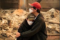 Ari Rivera (r) und Anderson Hao umarmen sich vor ihrem zerstörten Haus in Altadena. Viele Menschen haben ihr gesamtes Hab und Gut verloren. - © John Locher/AP/dpa