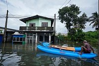 Überschwemmungen in Sri Lanka: Ein Mann ist mit seinem Boot in einem überfluteten Gebiet unterwegs. - © Eranga Jayawardena/AP/dpa