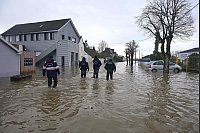 Mitglieder des Sicherheitskorps CRS gehen durch eine überflutete Straße in Redon, Westfrankreich. Drei aufeinanderfolgende Tiefdruckgebiete bescheren dem Nordwesten Frankreichs Hochwasser und Überschwemmungen. - © Damien Meyer/AFP/dpa