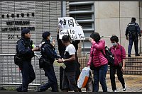 Ein Polizist versucht, eine Frau daran zu hindern, vor dem Gericht in West Kowloon ein Transparent mit der Aufschrift «Gott ist mit dir» in englischer und chinesischer Sprache zu zeigen. Ein Gericht in Hongkong hat 45 Demokratie-Aktivisten zu Haftstrafen von bis zu zehn Jahren verurteilt. - © Liau Chung-Ren/ZUMA Press Wire/dpa