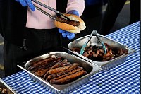 Ein Arbeiter bereitet in der Marrickville Public School in Sydney, Australien, eine "Demokratie-Wurst" für jemanden zu, der bei den Parlamentswahlen seine Stimme abgegeben hat. Der verführerische Duft brutzelnder Würstchen ist in Australien fester Bestandteil jeder Wahl. Traditionell steht vor vielen Wahllokalen ein Grill, an dem sich die Bürger mit einer Art Hot Dog (Bratwurst im weichen Brötchen mit Zwiebeln, Senf und Ketchup) stärken können: dem sogenannten «Democracy Sausage». - © Rick Rycroft/AP/dpa