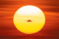 Ein Flugzeug setzt vor der untergehenden Sonne auf dem Flughafen Frankfurt zum Landeanflug an. - © Boris Roessler/dpa