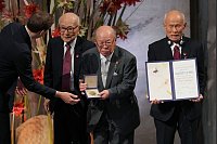 Friedensnobelpreis 2024: Der Vorsitzende des Nobelkomitees, Jørgen Watne Frydnes (l-r), steht mit Terumi Tanaka, Shigemitsu Tanaka und Toshiyuki Mimaki, den Vertretern des diesjährigen Friedensnobelpreisträgers Nihon Hidankyo (Japan Confederation of A- and H-Bomb Sufferers Organizations), bei der Verleihung des Friedensnobelpreises im Rathaus von Oslo. - © Kin Cheung/AP/dpa