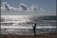 Eine Frau fotografiert an einem windigen Tag mit ihrem Handy am Strand von Arenal auf Mallorca. - © Clara Margais/dpa