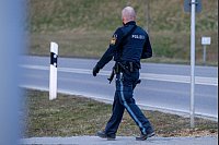 Ein bewaffneter Polizist geht auf einer Straße am Ortsrand von Parsberg. - © Armin Weigel/dpa