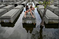 Frauen stellen nach Tropensturm Trami auf einem überschwemmten Friedhof auf den Philippinen Kerzen auf. - © Aaron Favila/AP/dpa