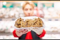 Ein Verkäuferin präsentiert auf dem Erfurter Weihnachtsmarkt einen Stollen. - © Jacob Schröter/dpa