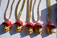 Ketten mit dem Konterfei von Donald Trump stehen bei einer Wahlkampfveranstaltung zum Verkauf. - © Evan Vucci/AP