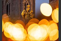 Eine goldene Marienfigur steht auf dem Marienplatz in München im Licht des umliegenden Weihnachtsmarkts. - © Peter Kneffel/dpa