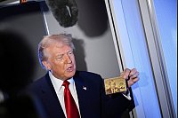 Präsident Donald Trump hält die goldene 5-Millionen-Dollar-Karte hoch, während er an Bord der Air Force One auf dem Weg nach Miami zu Reportern spricht. - © Uncredited/AP/dpa
