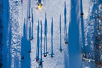 Die Aufnahme einer Fotodrohne zeigt aus ungewohnter Perspektive, wie Wintersportler im Skigebiet Erlebnisberg Altenberg neben einem Skilift die Piste hinunterfahren. - © Sebastian Kahnert/dpa