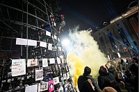 Ein Demonstrant befestigt eine georgische Flagge an einem vor dem Parlamentsgebäude aufgestellten künstlichen Weihnachtsbaum. - © Pavel Bednyakov/AP