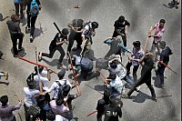 Studenten schlagen einen Polizisten mit Stöcken - © Anik Rahman/AP/dpa