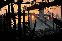Die Sonne geht hinter dem vom Feuer verwüsteten Stadtteil Pacific Palisades auf. - © Damian Dovarganes/AP/dpa