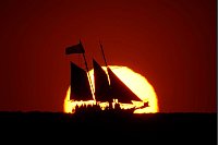 Ein Segelboot zeichnet sich gegen die untergehende Sonne ab, während es im Golf vor der Küste von Treasure Island in Florida segelt. - © Charlie Riedel/AP/dpa