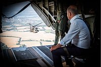 Bundeskanzler Olaf Scholz schaut aus der offenen Heckklappe eines CH 53 Helikopters der Bundeswehr auf einen Begleithubschrauber. - © Steffen Kugler/Presse- und Informationsamt der/dpa