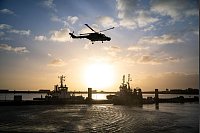 Die Besatzung eines Bundeswehrhubschraubers winkt Angehörigen, die am Pier des Marinestützpunktes in Wilhelmshaven auf die «Hamburg» warten - © Sina Schuldt/dpa