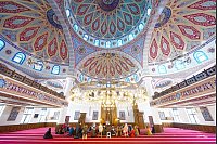 Besucher sitzen am Tag der offenen Moschee bei einer Führung im prächtigen Innenraum in der DITIB-Merkez Moschee in Duisburg auf dem Teppich im Gebetsraum. - © Henning Kaiser/dpa
