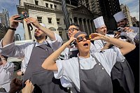 Angestellte eines Restaurants in Manhattan machen eine Pause, um die Sonnenfinsternis zu betrachten. - © John Minchillo/AP/dpa