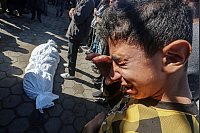 Ein Junge weint neben einem der Toten des israelischen Angriffs auf Deir al-Balah - © Omar Ashtawy/APA Images via ZUMA Press Wire/dpa