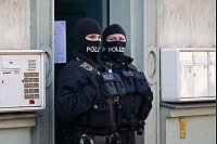 Polizisten stehen während einer Razzia gegen mutmaßliche Rechtsextreme in einem Hauseingang im Dresdner Stadtteil Cotta. - © Sebastian Kahnert/dpa