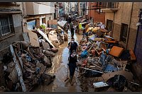 In Spanien bleibt die Situation nach den Überschwemmungen dramatisch. Hier gehen Menschen durch eine Straße voller Trümmer, Schlamm, beschädigter Möbeln und Müll in Valencia. - © Emilio Morenatti/AP/dpa