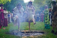 Frauen springen beim Beltane-Festival am Glastonbury Chalice Well in England über das Feuer. - © Ben Birchall/PA Wire/dpa