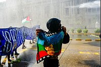 Ein Indigener hält eine Mapuche-Flagge, während die Polizei bei einem Marsch zur Forderung nach einem autonomen Territorium für Chiles Indigene und die Freilassung von Pro-Mapuche-Häftlingen Wasser und Tränengas auf Demonstranten schießt. - © Esteban Felix/AP/dpa