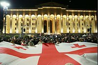 Demonstranten mit einer riesigen georgischen Nationalflagge versammeln sich vor dem georgischen Parlamentsgebäude, um die Freilassung politischer Gefangener und Neuwahlen zu fordern. - © Zurab Tsertsvadze/AP/dpa
