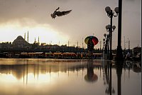 Eine Frau schützt sich mit einem Regenschirm vor leichtem Schneefall an der Strandpromenade von Karakoy. - © Francisco Seco/AP/dpa