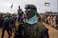 Martialischer Auftritt: Vermummte und bewaffnete Kämpfer der Terrororganisation Hamas gehen in Stellung, bevor sie die Leichen von vier israelischen Geiseln, darunter eine Mutter und ihre beiden Kinder, die seit langem für tot gehalten wurden, dem Roten Kreuz in Chan Junis im südlichen Gazastreifen übergeben wollen. - © Abdel Kareem Hana/AP/dpa