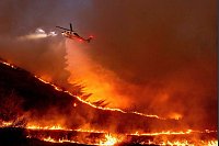 Flug durch das Inferno: Ein Hubschrauber wirft Wasser auf das Kenneth-Feuer in den West Hills von Los Angeles. - © Ethan Swope/AP/dpa