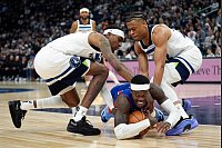 NBA Basketball: Detroit Pistons-Guard Dennis Schröder (M), fällt, während Minnesota Timberwolves-Forward Jaden McDaniels (l) und Guard Jaylen Clark (r) um den Ballbesitz kämpfen. - © Abbie Parr/AP/dpa