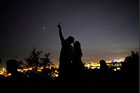 Ein junges Paar steht auf einer Mauer und betrachtet den Himmel an einem Aussichtspunkt über Lissabon während eines landesweiten Stromausfalls. - © Armando Franca/AP/dpa