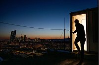 Ein Mann betritt hoch über den Dächern von Frankfurt ein Treppenhaus, während die Sonne hinter dem Horizont verschwunden ist. - © Boris Roessler/dpa